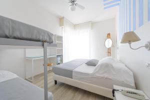 a white bedroom with a bunk bed and a desk at Hotel Nobel in Gabicce Mare