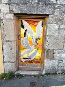 a window with two white birds painted on the side of a building at Crows Nest - cosy, tiny cottage in Castletown