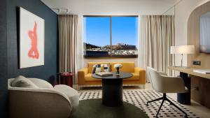 a living room with a yellow couch and a table at InterContinental Athenaeum Athens by IHG in Athens