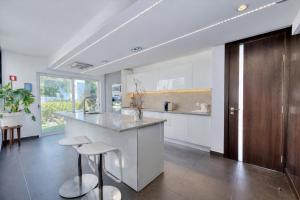 a kitchen with white cabinets and a counter and stools at CASA DO LAGO, Infinity Pool, Mountains & Sea view in Estói