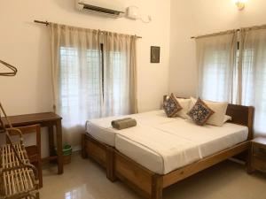 a bedroom with a bed with white sheets and windows at Tattwamasi Ayuryoga with Breakfast and Yoga in Varkala