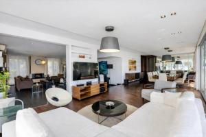 a living room with white furniture and a large screen tv at CASA DO LAGO, Infinity Pool, Mountains & Sea view in Estói