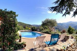 two chairs and a swimming pool with mountains in the background at mondonlehaut in Saint-Fortunat-sur-Eyrieux