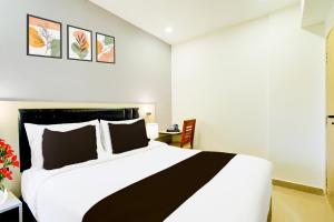 a bedroom with a large white bed and a desk at Townhouse Aarav Business Hotel in Hyderabad
