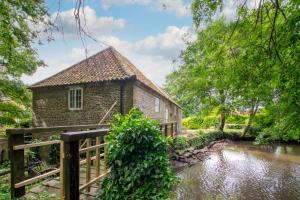 a brick building with a fence next to a river at Snettisham Watermill Pet Friendly Historic Listed Property in Snettisham