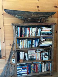 a book shelf filled with books next to a wall at Shackmatack in Tenants Harbor