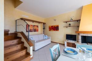 a living room with a white couch and a television at Hostdomus - Villa Bea free garage and pool in Magliolo