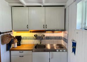 a kitchen with a sink and white cabinets at Cozy Studio on Utö Near Beach & Restaurant in Utö