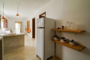 a kitchen with a white refrigerator and a counter at Evoé Caraíva in Caraíva +28 photos