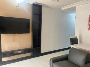 a living room with a tv and a chair at Mobile Unique Apt in Ikeja