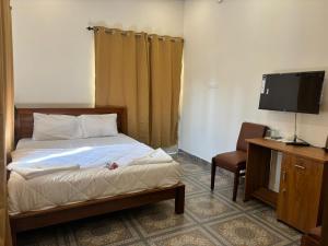 a bedroom with a bed and a tv and a chair at Aagneyam villa in Kozhikode