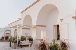 a white building with a patio with chairs and plants at Corte Vespro in Ugento