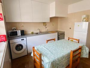 a kitchen with a table and a sink and a microwave at SwordFish Cliff Apartment in Peniche