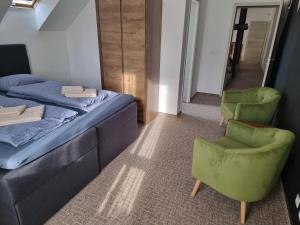 a bedroom with a bed and two green chairs at Munich Residence in Cristian