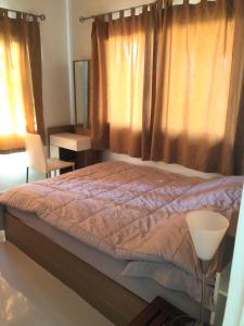 a bedroom with a bed and a window with curtains at Casa Seaside Rayong by Chate in Rayong