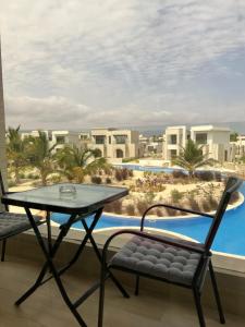 a balcony with a table and chairs and a pool at Oriole Havana Salalah in Salalah