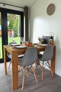 a dining room table with chairs and a clock on the wall at Tinyhouse Seeträumchen direkt am See mit Terrasse für 4 in Bodenwöhr +33 photos