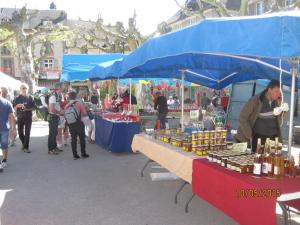 Eine Gruppe von Menschen steht auf einem Markt um einen Tisch mit Waren herum. in der Unterkunft Hotel Le Commerce in Neuville