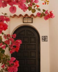a black door with a number above it with pink flowers at UNIO Ibiza - Adults Only in Cala Vadella