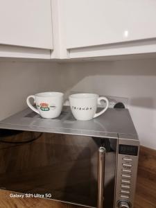 two coffee cups sitting on top of a microwave at Beluca homes Acklam in Middlesbrough