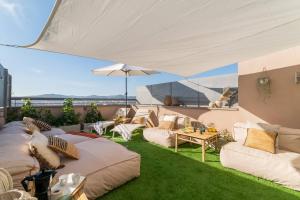 a patio with couches and a table and an umbrella at Penthouse with Private Terrace & Pool Access in Cornellà de Llobregat