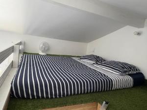 a bedroom with a large bed with striped sheets at Studio cosy avec piscine à 10 min Hossegor in Saint-Vincent-de-Tyrosse +18 photos