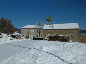 una chiesa con una strada innevata di fronte a un edificio di Gîtes des Gabriels a La Chapelle-en-Vercors