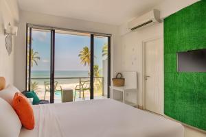 a bedroom with a bed and a view of the beach at Mask & Tide - Jetwing Select in Ambalangoda