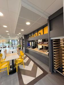 a restaurant with yellow chairs and tables and a wine cellar at B&B HOTEL Meaux in Meaux