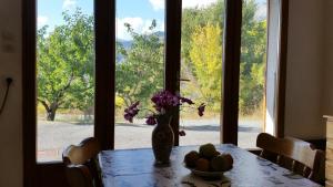 een tafel met een vaas met bloemen en een schaal met fruit bij Appartement Barcelonnette Ubaye, Provence in Enchastrayes