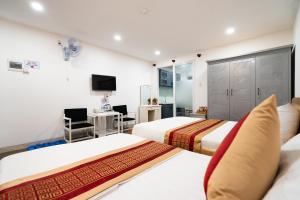 a hotel room with two beds and a desk at Helen Airport Hotel in Ho Chi Minh City
