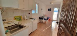 a kitchen with white cabinets and a sink and a table at 205 Mata, 80m vom Strand in Stanići +16 photos