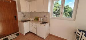 a small kitchen with white cabinets and a window at 205 Mata, 80m vom Strand in Stanići
