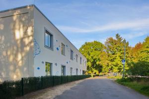 a white building with a fence next to a road at Gästehaus Gothensee in Heringsdorf
