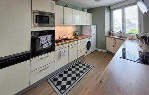 a large kitchen with white cabinets and a checkered floor at Superbe Appartement Vue Mer in Dunkerque