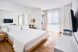a white bedroom with a white bed and a tv at Flamm Residences in Bodrum City