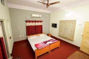 a bedroom with a bed and a ceiling fan at Hotel Evergreen in Āsansol