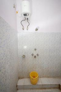 a bathroom with a yellow bucket and a light on the wall at Hotel Evergreen in Āsansol