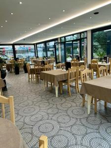 a restaurant with tables and chairs and windows at Hotel Kapri in Golem