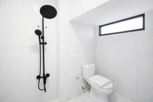 a white bathroom with a toilet and a shower at Arumi Experience Tasikmalaya Syariah in Tasikmalaya +17 photos