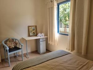 a bedroom with a bed and a desk and a window at Costa Family-Little house in the center in Santa Rita do Sapucaí