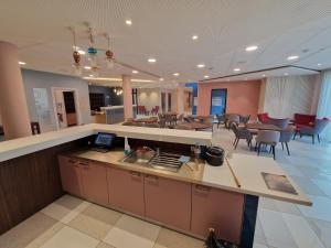 a kitchen with a counter and a cafeteria with tables and chairs at DOMITYS - Les Cristaux in Le Creusot