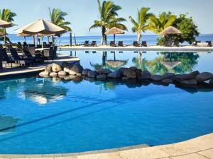 a pool at a resort with palm trees and the ocean at Fiji superbe views in Ndenarau Island