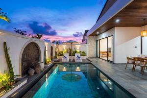 an indoor swimming pool in a villa with a dining area at Diwangkara Villa Pandawa in Ungasan