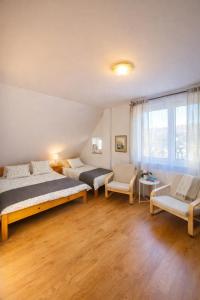 a bedroom with two beds and a couch and a chair at Apartamenty & Domek Gawędówka in Krościenko