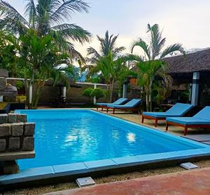 a swimming pool with benches and palm trees at Khair Lodge Ambanja in Ambanja