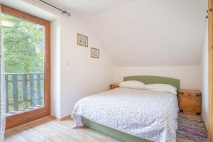 a bedroom with a bed and a large window at Vineyard Cottage Vrbek in Roginska Gorca