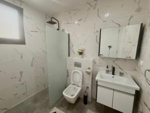 a white bathroom with a toilet and a sink at Sublime appartement avec Piscine, 2 chambres au Point E, Dakar in Dakar