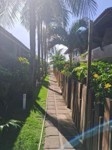 a sidewalk next to a fence with palm trees at Suíte Pé na Areia do Flamengo in Salvador