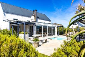 a home with a swimming pool and a house at The Bay Cottage in Pringle Bay
